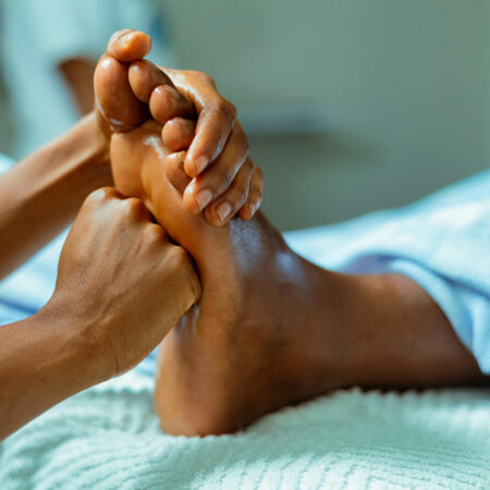 Eine Fachkraft führt eine Fußreflexzonenmassage an einem Patienten durch, wobei gezielt Druck auf spezifische Punkte am Fuß angewendet wird, die mit verschiedenen Körperorganen korrespondieren. Die Massage findet in einer entspannten Umgebung statt, wodurch Wohlbefinden und Gesundheit gefördert werden.